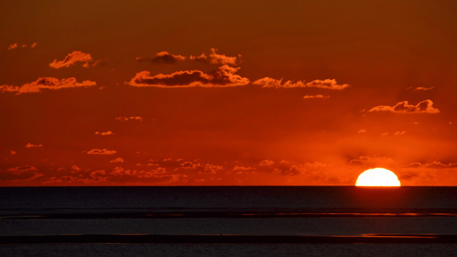 Sonnenuntergang am Meer halbe Sonne rot wenig Wolken Sandbänke