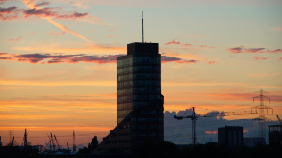 Channel Tower Hamburg Harburg Hochhaus vor Sonnenuntergang in der Stadt Kräne im Hintergrund Stromleitungen und Strommasten