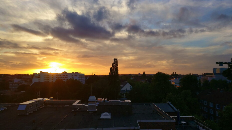 Beachclub Sky and Sand Aussicht Sonnenuntergang Wolken Helle Sonne hinter Haus goldener Himmel Blick über Häuser